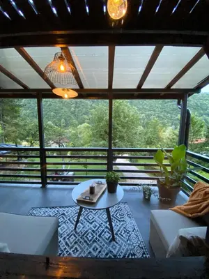 a living room with a table and a large window at Vikendica Bella in Bihać