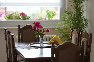 a dining room table with a vase of flowers on it at Apartment Home Sweet Home in Banja Luka