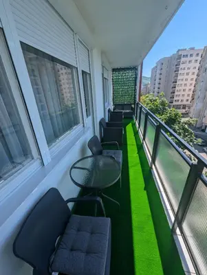 a balcony with chairs and a table and windows at Apartment Home Sweet Home in Banja Luka