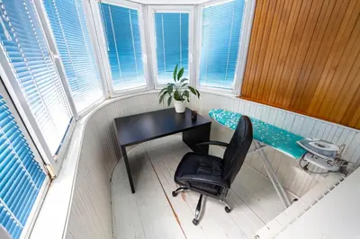 a desk and a chair in a room with windows at Spacious apartment (60sqm) with a balcony in Tuzla