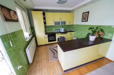 a kitchen with yellow cabinets and green tiles at Spacious apartment (60sqm) with a balcony in Tuzla