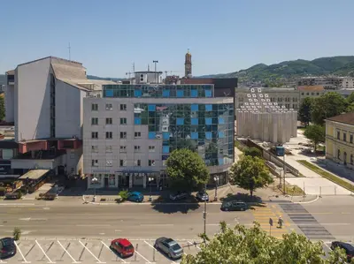 a large white building in a city with a parking lot at Rio apartments in Banja Luka