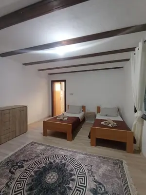a large room with two beds and a rug at Sobe RoomsBella in Ripač