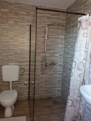 a bathroom with a shower with a toilet and a sink at Sobe RoomsBella in Ripač
