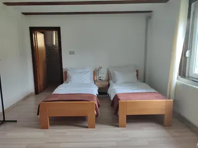 a room with two beds and two benches in it at Sobe RoomsBella in Ripač