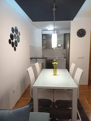 a dining room with a white table and white chairs at Apartman 
