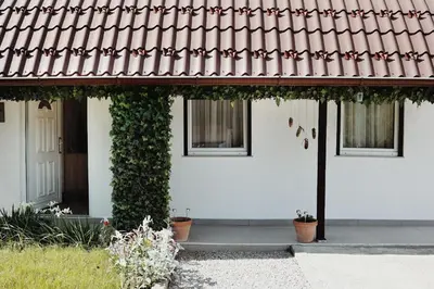 a white house with a red roof and potted plants at Holiday Home Casa Rondo in Bihać
