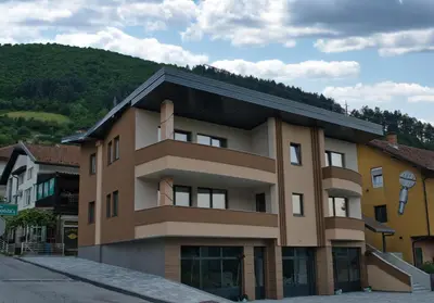 a brown building with a mountain in the background at SM Exclusive Apartments in Visoko