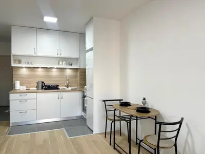 a kitchen with white cabinets and a table and chairs at Elegance Self check-in Free Parking in Tuzla