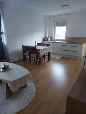 a living room with a table and a kitchen at Good Vibes in Bihać