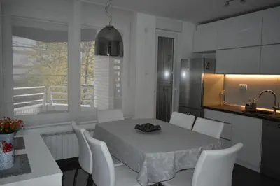 a kitchen with a table and white chairs in a kitchen at MLK Diamond Apartments in Starčevica
