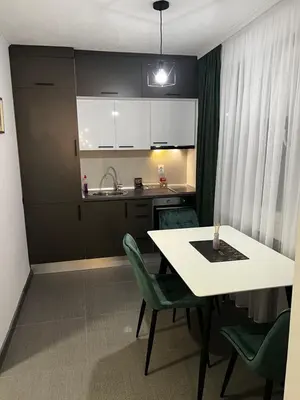 a kitchen with a white table and green chairs at Apartman 10 in Banja Luka