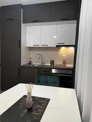 a kitchen with black and white cabinets and a table at Apartman 10 in Banja Luka