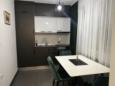 a kitchen with a white table and green chairs at Apartman 10 in Banja Luka