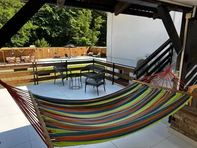 a hammock on a patio with a table and chairs at Holiday home with private pool ''Lux Banja Luka'' in Banja Luka