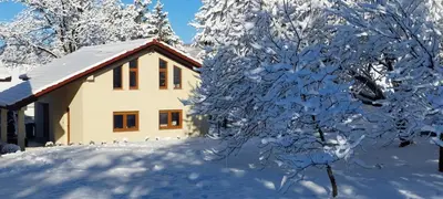 a snow covered tree next to a house at Apartman Marin in Livno