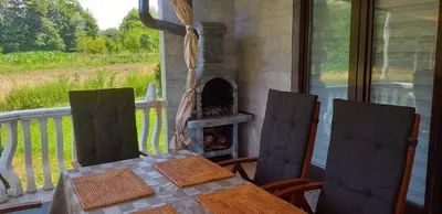 a table and chairs on a porch with a fireplace at Vikendica M&M / Vacation home M&M in Visoko