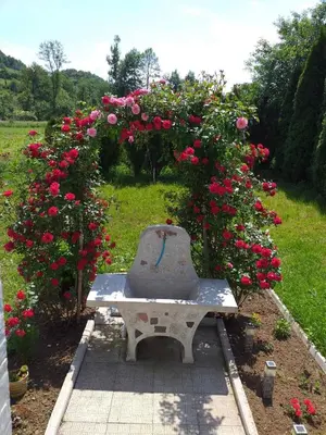 a stone bench in a garden with pink roses at Vikendica M&M / Vacation home M&M in Visoko