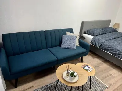 a living room with a blue couch and a bed at Apartman UMA in Bihać