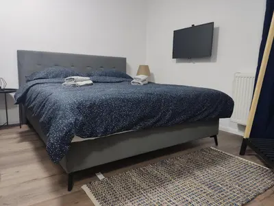 a bedroom with a bed with a blue comforter and a television at Apartman UMA in Bihać