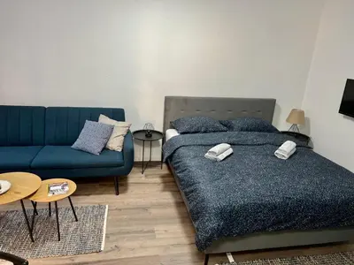 a bedroom with a bed and a blue couch at Apartman UMA in Bihać