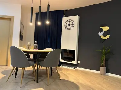 a dining room with a table and a clock on a wall at Apartman Ena Fojnica in Fojnica
