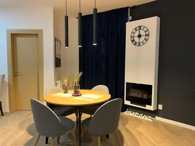 a dining room with a table and chairs and a clock at Apartman Ena Fojnica in Fojnica