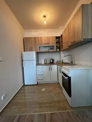 a kitchen with a white refrigerator and wooden cabinets at Apartman Paradise Fojnica in Fojnica