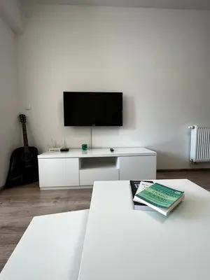 a white living room with a television and a book on a table at Apartman Paradise Fojnica in Fojnica