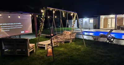 a swing in a yard with a pool at night at Villa Park Banja Luka in Banja Luka