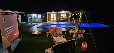 a backyard with a swing and a fire pit at night at Villa Park Banja Luka in Banja Luka