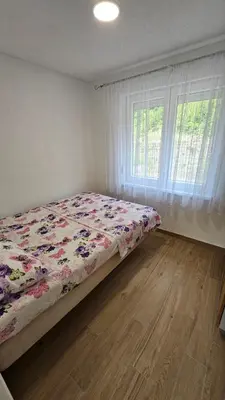a bedroom with a bed with a floral comforter and a window at Villa Park Banja Luka in Banja Luka