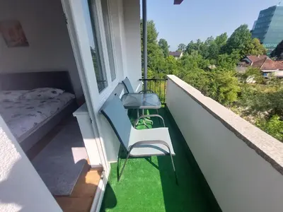 a balcony with a bed and two chairs on a balcony at Apartman 