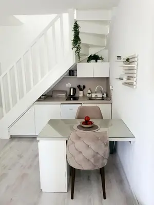a white kitchen with a table and a chair at Apartman DANA in Banja Luka