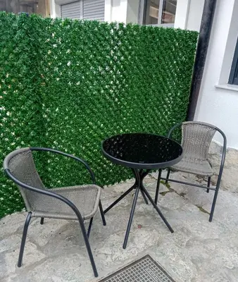 two chairs and a table and two chairs in front of a hedge at Apartman DANA in Banja Luka