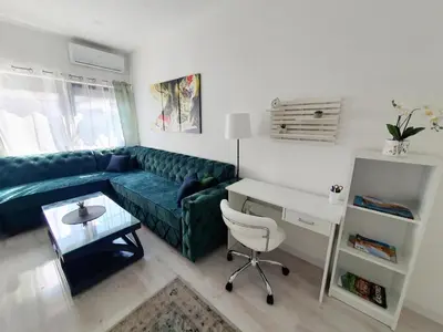 a living room with a green couch and a desk at Apartman DANA in Banja Luka
