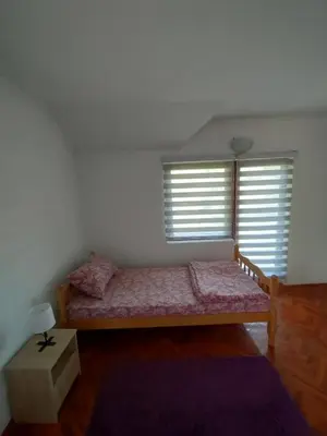a small bedroom with a bed and two windows at Vikendica Savić in Šipovo