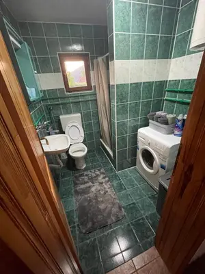 a green tiled bathroom with a toilet and a sink at Vikendica Savić in Šipovo