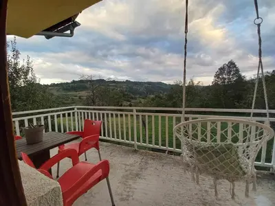 a porch with chairs and a table and a swing at Vikendica Savić in Šipovo