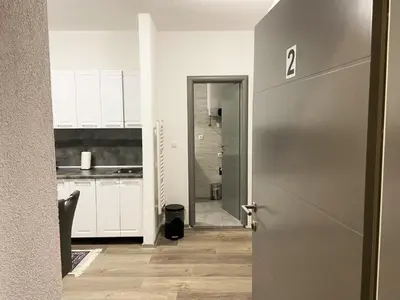a hallway with a door to a kitchen with white cabinets at Apartman Kraljica 2 in Kupres
