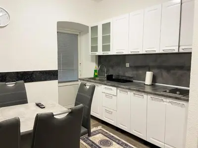 a kitchen with white cabinets and a table with chairs at Apartman Kraljica 2 in Kupres