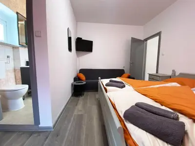 a bedroom with two beds and a bathroom with a toilet at Soba za goste Kraljica 3 in Kupres
