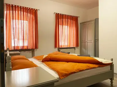 a bedroom with two beds with orange sheets at Soba za goste Kraljica 3 in Kupres