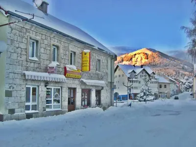 a building in the snow with a mountain in the background at Apartman Kraljica 1 in Kupres