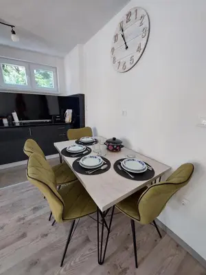 a dining room table with chairs and a clock on the wall at Apartman Cincar in Livno
