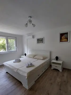 a white bedroom with a large bed and two windows at Apartman Cincar in Livno
