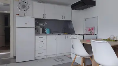 a kitchen with white cabinets and a table with white chairs at Dina's house in Cazin