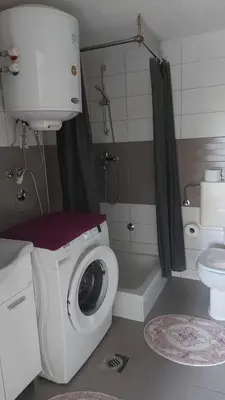 a bathroom with a washing machine and a toilet at Dina's house in Cazin