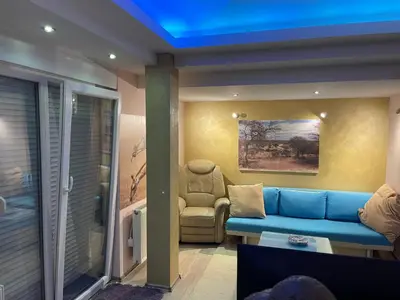 a living room with a blue couch and a chair at Amsterdam in Banja Luka
