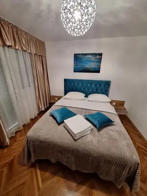 a bedroom with a bed with blue pillows and a chandelier at centar apartment in Banja Luka